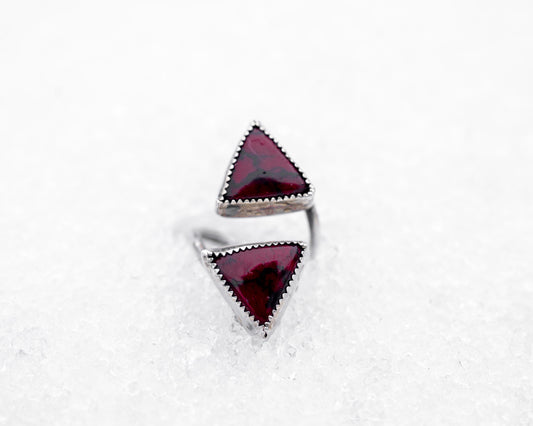 Sterling silver open ring featuring two triangular bloody bison jasper stones pointed inward. The piece rests on icy snow, giving it a mystical, duality-driven appearance with a sharp, ceremonial aesthetic.

